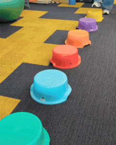 Animated GIF of feet stepping across stepping stones in the clinic, with a 90-degree tilt animation simulating a balance challenge
