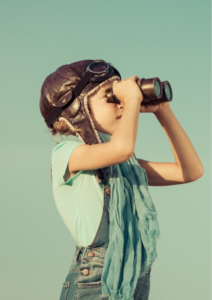 Child in vintage pilot cap and goggles looking through binoculars, representing the Koru Explorers holiday program for kids