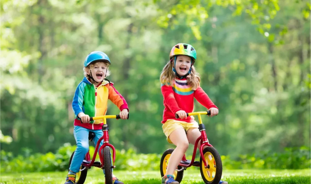 Two children riding balance bikes outdoors at a Koru Allied Therapies bike skills group